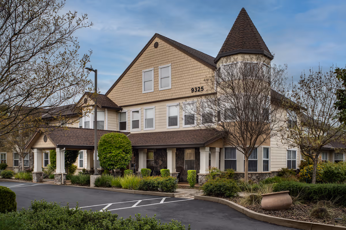 Front view of The Meadows Senior Living building with a turret and landscaping.