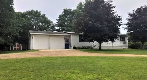 Single-story facility exterior with a two-car garage, driveway, and surrounding trees.