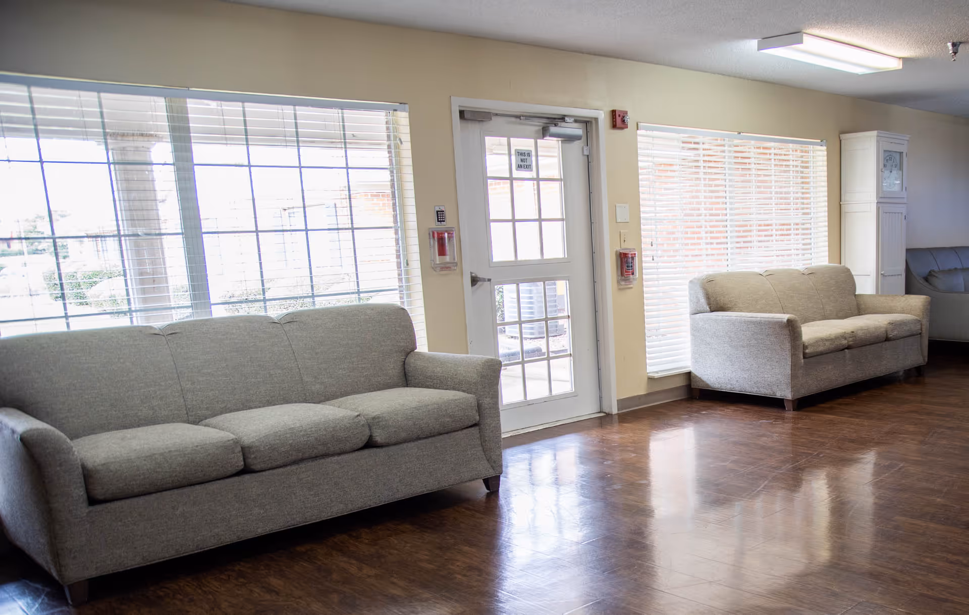 Bright seating area with two gray sofas, large windows, and a glass door.