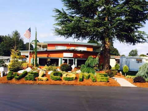 Exterior view of a senior living facility with landscaped front and flagpole.