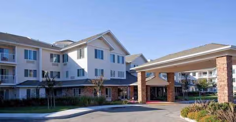 Exterior view of a Holiday Golden Oaks senior living building with brick columns and landscaped entrance.