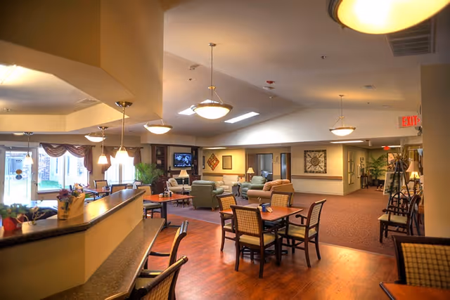 Spacious furnished common area with dining tables, chairs, a counter, and lounge seating under pendant lights.