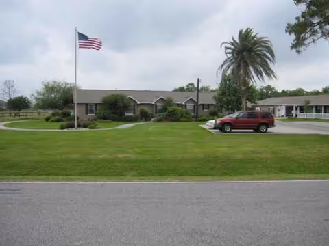 Exterior view of Evening Star Personal Care Home with flag, lawn, and parked cars
