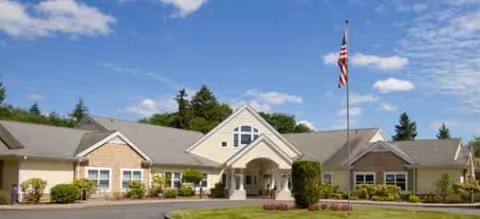 Wide view of Brookdale Olympia West facility exterior with entrance and flag.