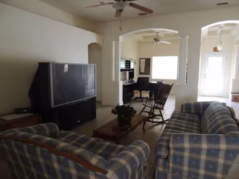 Cozy living room with plaid sofas, coffee table, TV, and adjacent kitchen area.