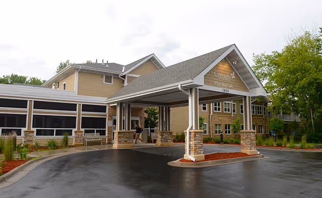 Front entrance canopy and driveway of Cerenity Residence White Bear Lake senior living facility with a covered porte-cochère and landscaped grounds.