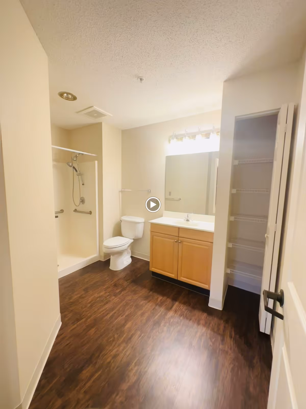 Spacious bathroom with a walk-in shower, toilet, vanity with mirror, and an open linen closet.