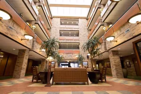 Atrium lobby with balconies, seating, plants, and a skylighted ceiling.