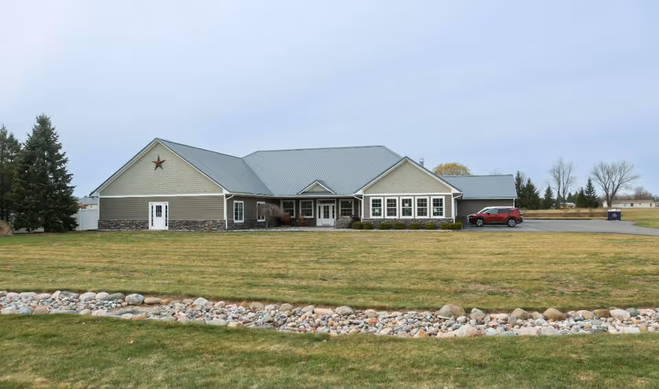 Senior living facility with light exterior, sloped metal roof, and landscaped front lawn