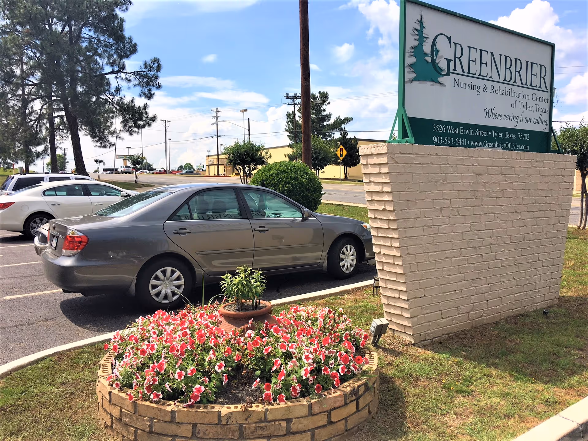 Parking lot with cars, a flowerbed and a large Greenbrier Nursing & Rehabilitation Center sign.