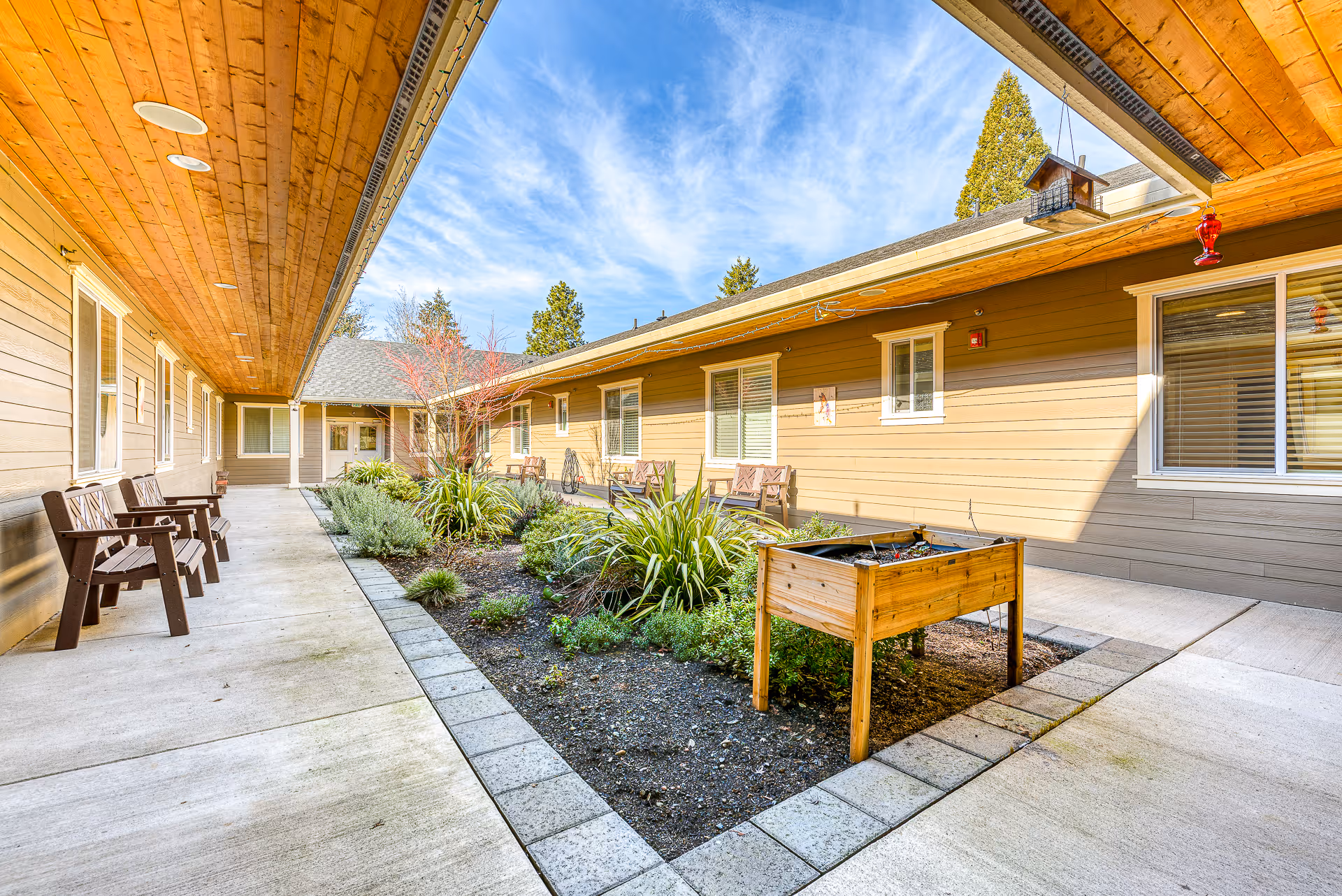 Covered courtyard with walkways, benches, landscaped planting beds and a raised wooden planter.