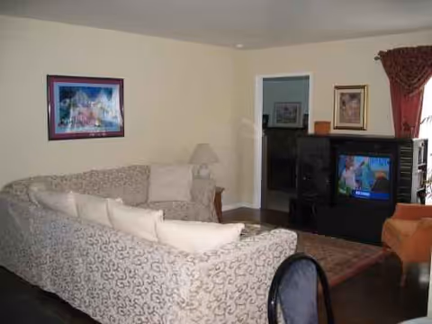 Cozy senior living facility living room with patterned sofa, lamp, rug, and a TV.
