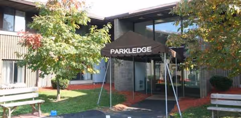 Exterior view of Parkledge Arms entrance with trees, benches, and a black canopy.