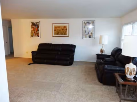 A furnished living room with black leather sofas and wall art.