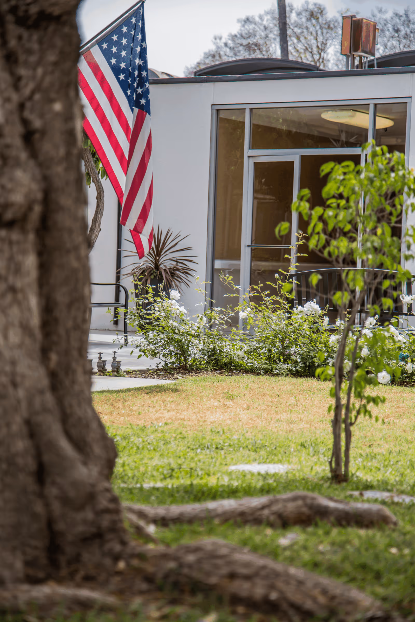 Exterior view of Brighton Care Center entrance with an American flag and surrounding greenery.
