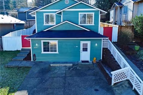 Front view of a teal two-story house with white railings and driveway