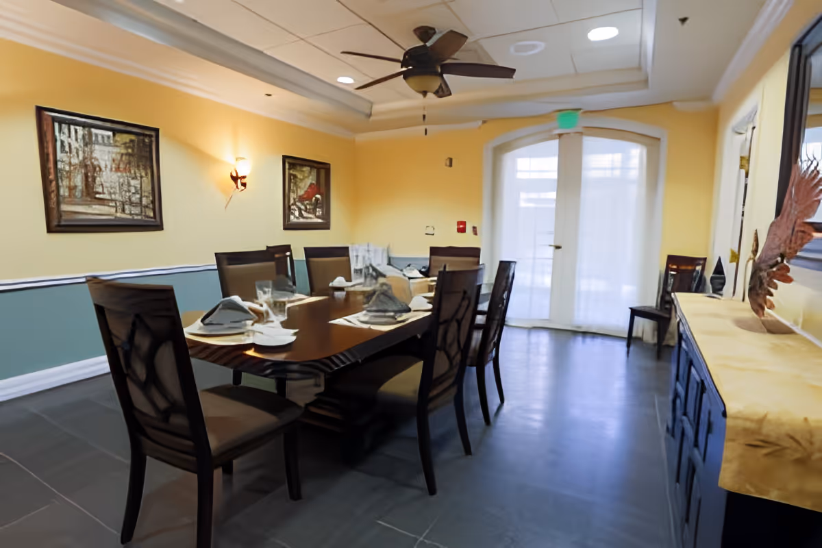 Dining room with a long wood table set for a meal, chairs, wall art, and double glass doors.