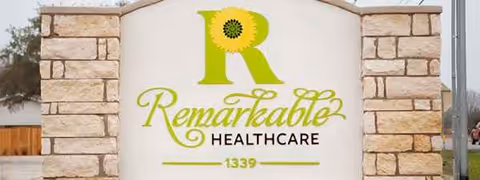 Outdoor stone sign at the facility entrance with Remarkable Healthcare logo.