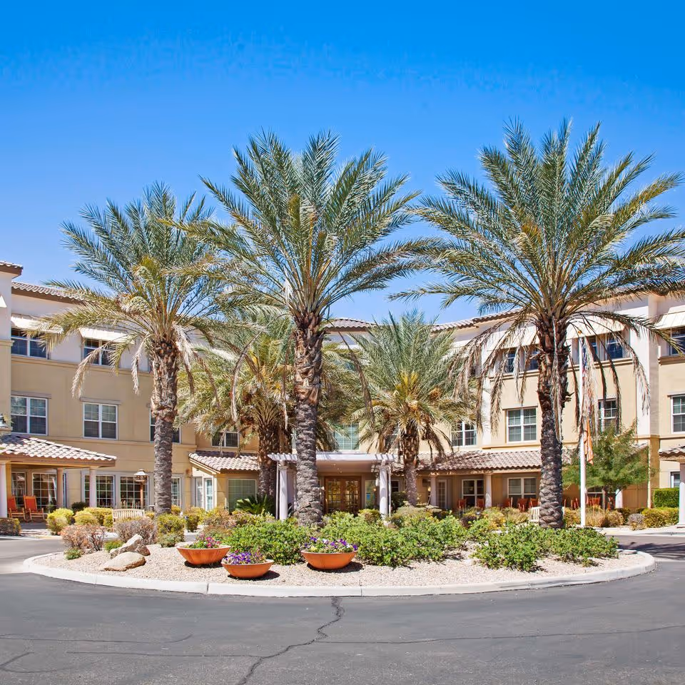 Sunrise at River Road exterior with palm trees, circular drive, and landscaped entrance.