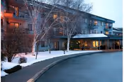 Snow-covered Evergreen Estates exterior with a curved driveway and lit entrance.