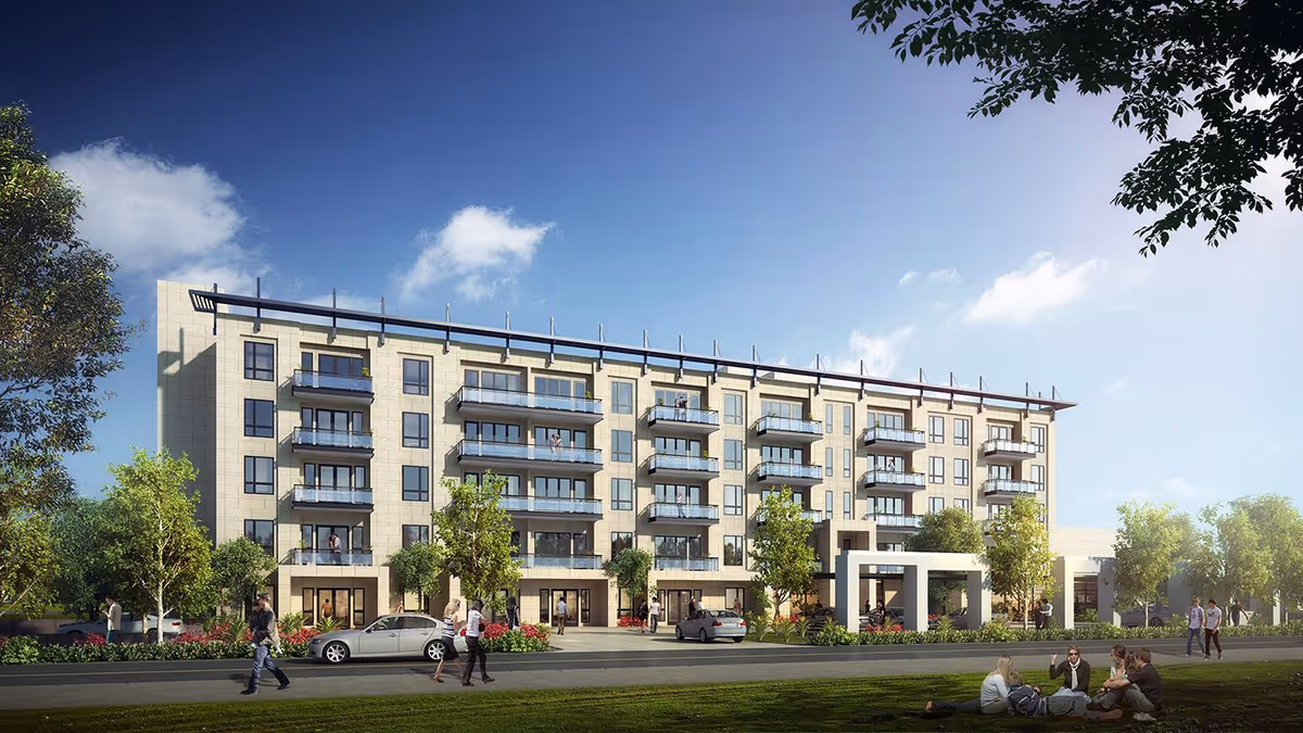 Exterior view of a modern, multi-story senior living facility with balconies, surrounded by trees and greenery. People are walking on the sidewalk and sitting on the grass in front of the building under a clear blue sky.