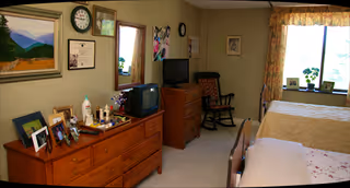 Cozy bedroom with two single beds, a dresser, TV, chairs, and curtained window.
