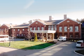 Brooksby Village exterior with red brick, covered entrance, and parked cars.