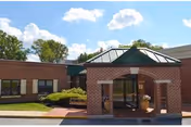 Frederick Villa Healthcare entrance with brick facade, green awning, and potted plants.