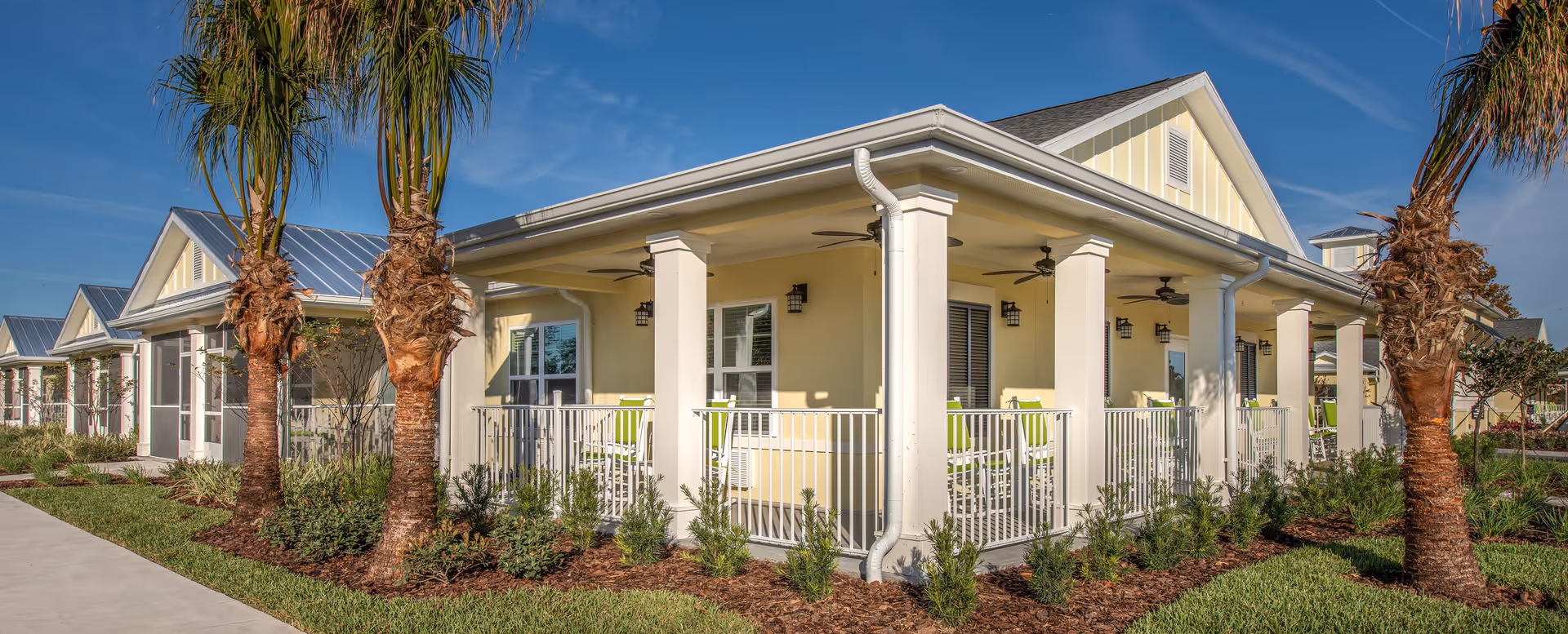 Exterior view of The Addison of Port Orange with a covered porch and palm trees.