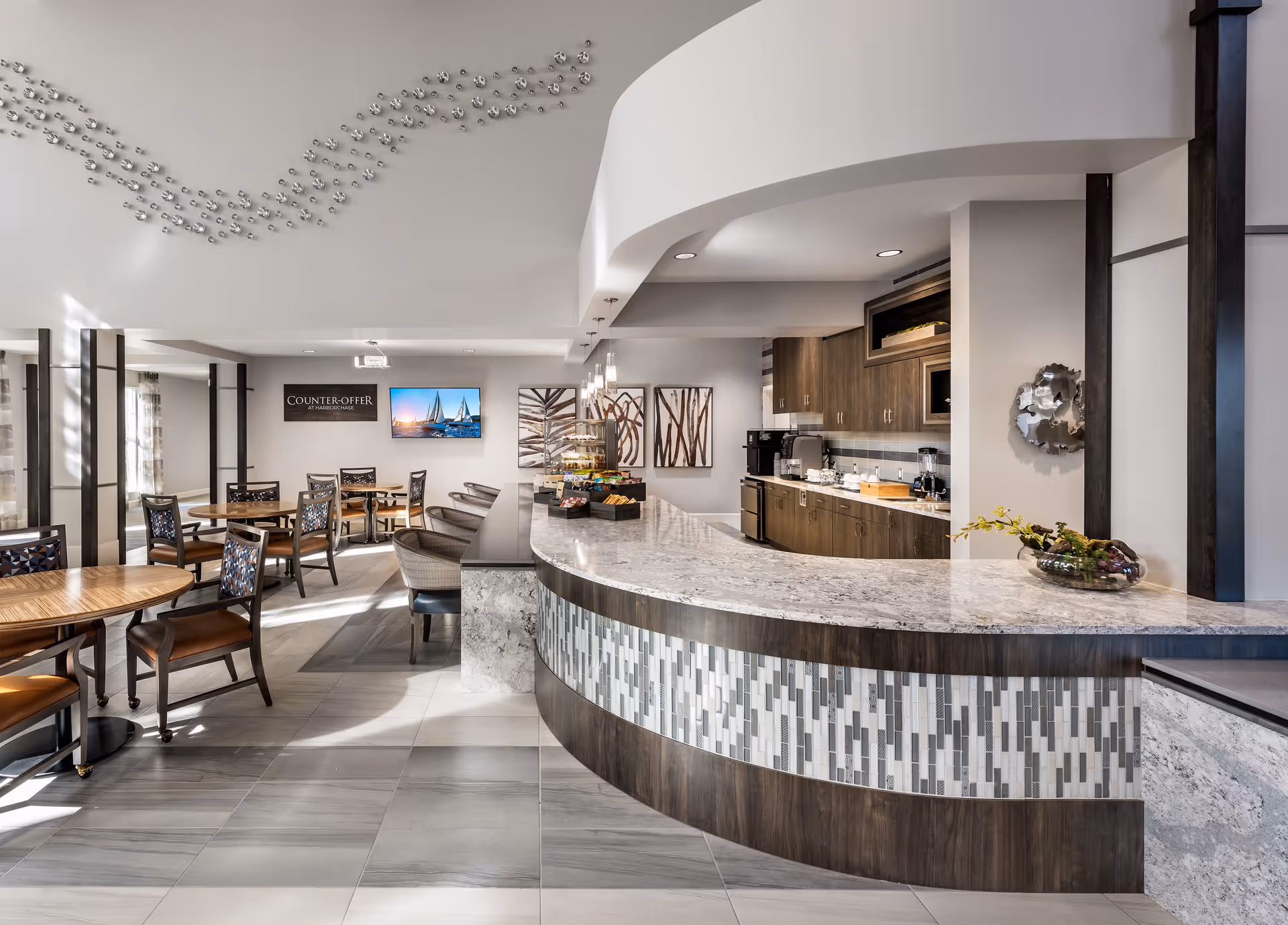 Spacious modern dining area with a curved marble-topped service counter, seating tables, and a food service/kitchenette area.