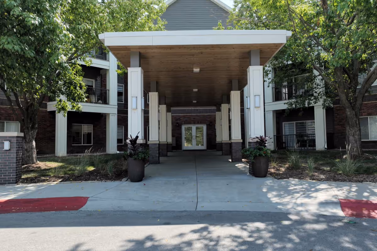 A covered entrance with white columns and double doors at Arboretum Village senior living facility.