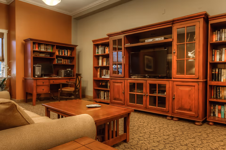 Cozy living room with a large wooden entertainment center holding a TV, bookshelves, a coffee table and a sofa.