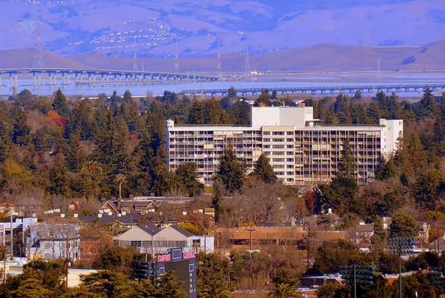 Channing House, a large multi-story senior living building, surrounded by trees in a suburban setting.