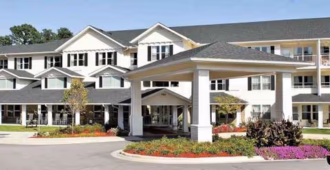 A multi-story senior living building with a covered entrance and landscaped front.