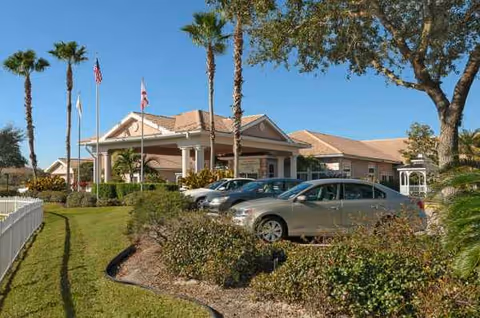 Life Care Center of Sarasota front entrance with palm trees, flags, and parked cars.