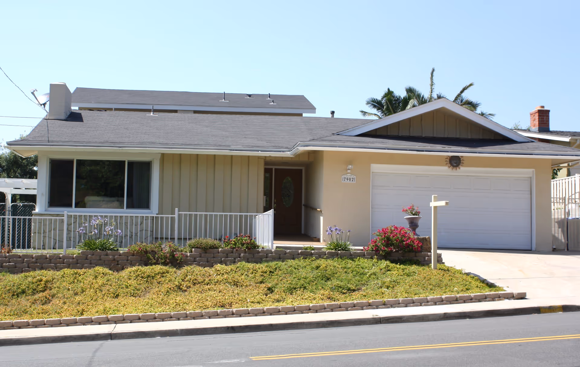 Single-story suburban home with an attached two-car garage, front porch, and landscaped low hedge yard.