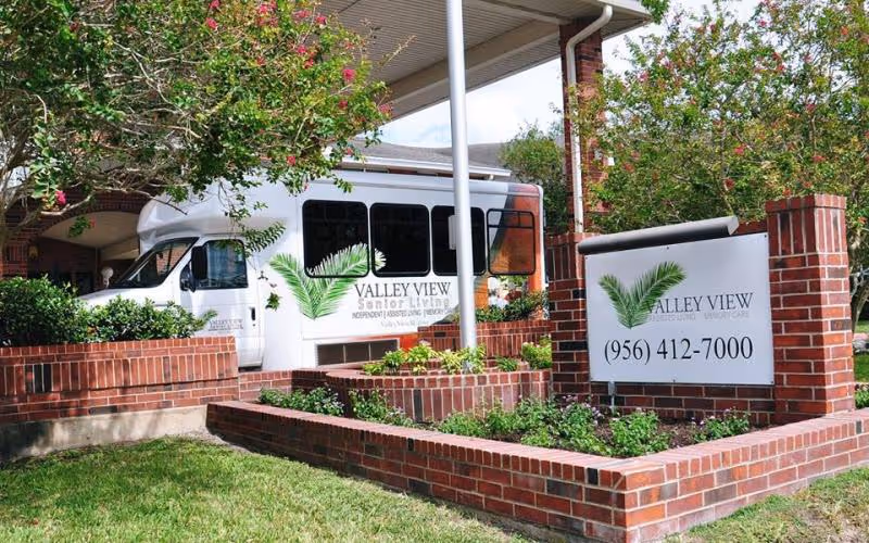 Exterior view of Valley View Senior Living entrance with a bus and sign.