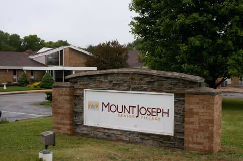 Stone sign reads Mount Joseph Senior Village in front of a brick building.