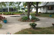Outdoor courtyard at Martina Place Assisted Living with a circular garden, benches, and trees.