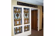 Stained glass panels next to an open wooden doorway under a sign reading 'Edith Crouse Memorial Chapel' in an interior hallway.