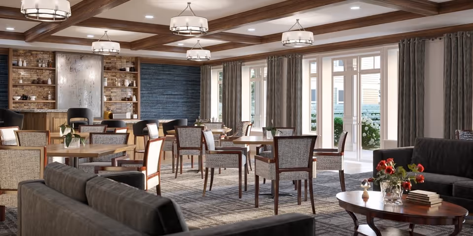 Bright communal dining and lounge area with tables, chairs, sofas, chandeliers and large windows.