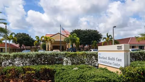 Front view of Boca Circle Rehabilitation Center with landscaping, sign, and flag