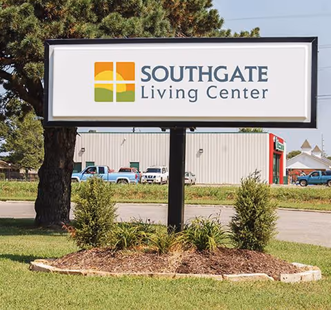An outdoor sign for Southgate Living Center with landscaping and a building in the background.