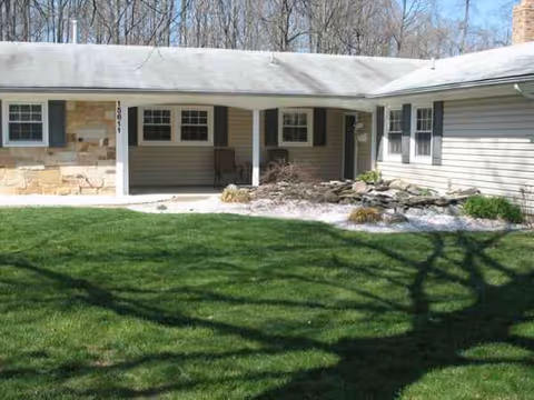 Single-story assisted living facility exterior with a covered porch and manicured green lawn.