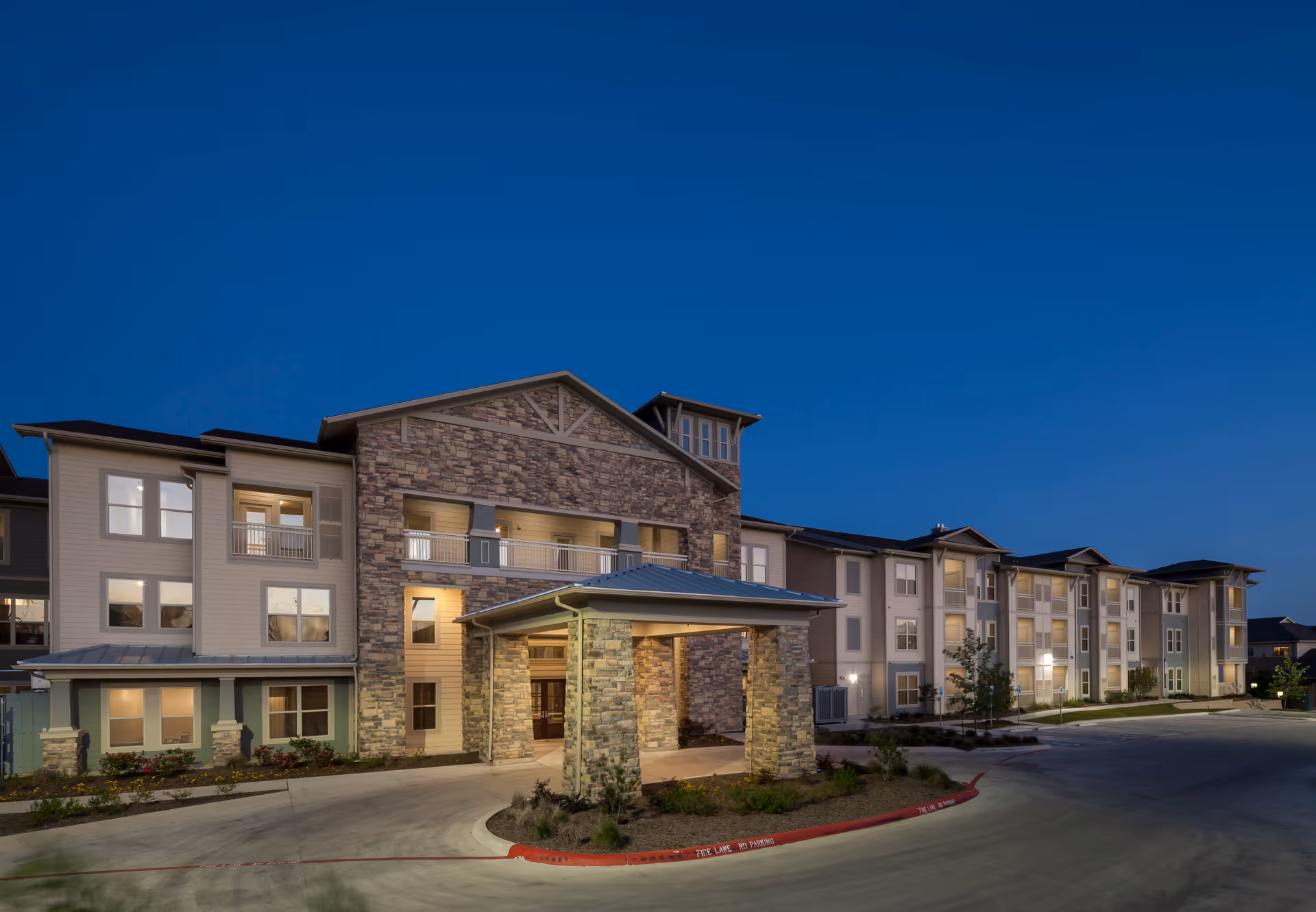 Exterior view of Discovery Village Stone Oak, a multi-story assisted living facility at dusk.