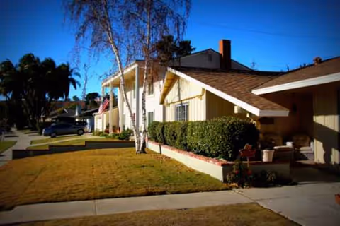 Exterior view of a single-story senior living facility with a front porch and lawn.