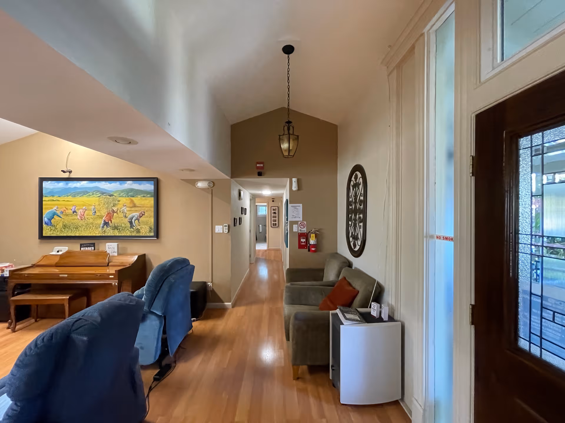 Entryway lounge with seating, a piano on the left, and a hallway leading further into the facility.