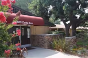 Exterior entrance to a senior care facility with brick walls and greenery.