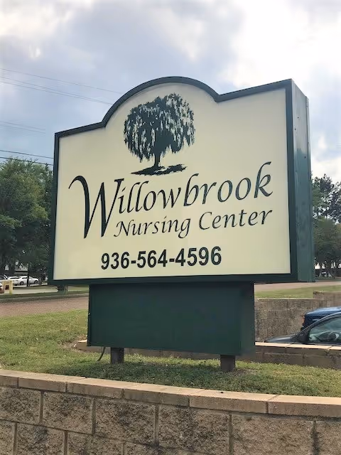 Large roadside sign for Willowbrook Nursing Center featuring a willow tree logo and a phone number.