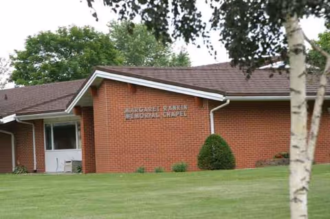 Brick senior living facility exterior with lawn and a memorial chapel sign
